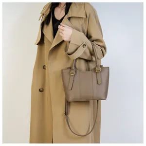 Detail of lychee textured dark brown leather tote bag with elegant gold metal hardware
