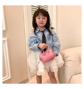Pink mini crossbody bag for kids with metal chain strap shown on child model