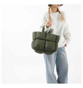 Army green quilted puffer tote bag detail showing padded texture on casual white outfit