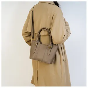 Side view of model wearing a brown lychee pattern leather tote bag with gold hardware