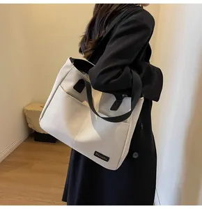 Detail view of a large cream canvas tote bag with black straps and Banatu logo tag