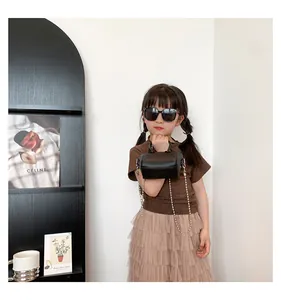 Toddler wearing a black mini crossbody bag with a metal chain and lychee texture