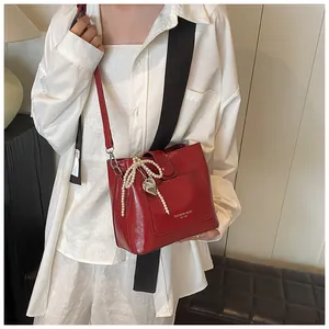 Détail du sac seau rouge brillant avec nœud en perles et pendentif en forme de cœur