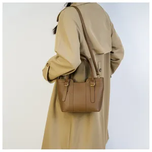 Brown lychee leather bucket bag styled with a beige trench coat for a commuter look