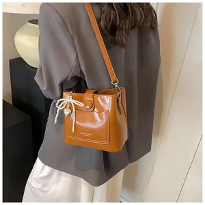 Détail d'un sac seau vintage marron avec pendentif cœur en perle et texte de mode