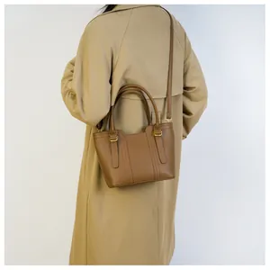 Brown litchi leather bucket bag shown on a model wearing a khaki trench coat