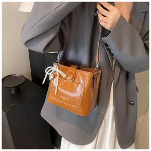 Détail d'un sac seau marron brillant avec nœud en perles et pendentif cœur élégant