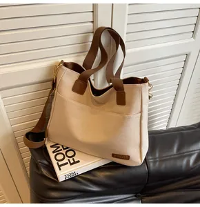 Close-up of off-white canvas tote bag with brown straps on black leather seat