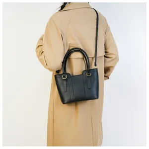 Detail view of black pebble leather crossbody bag on khaki coat for commute