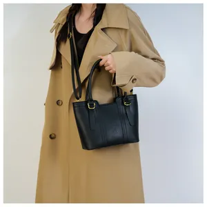 Detail of black lychee grain leather handbag with gold hardware and shoulder strap
