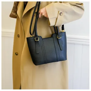 Detail of black pebbled leather bucket bag featuring gold hardware and commute style