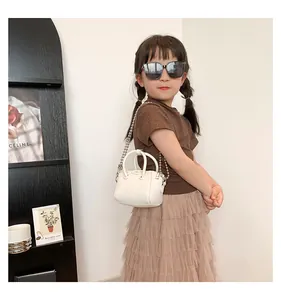 Detailed view of child model wearing white mini crossbody bag with silver ball chain