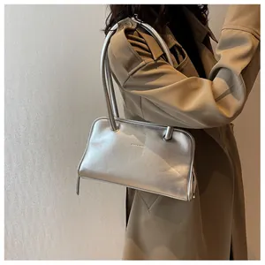Detail shot of a matte silver shoulder bag featuring long handles and clean stitching