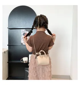 Toddler girl wearing beige textured PU leather mini bag with silver chain and dual handles