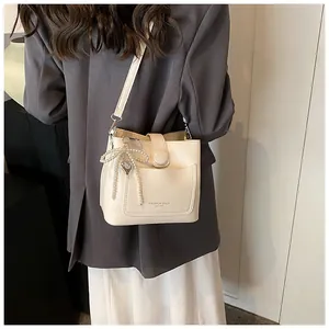 Détail du sac seau crème avec breloque nœud en perles et pendentif en forme de cœur