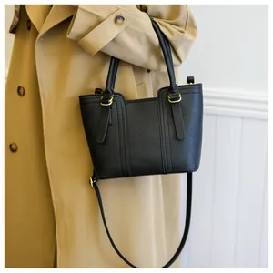Detail of black pebbled leather handbag with gold metal buckles and cylindrical handles