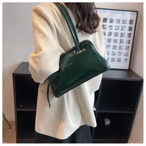 Detailed close-up of a glossy green leather shoulder bag with fine metallic brand lettering