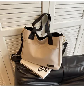 Detail of beige canvas tote bag with black handles and long shoulder strap for commuting