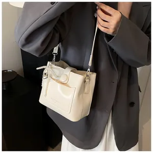 Détail du sac seau crème avec nœud en perles et pendentif cœur, vue de côté sur modèle