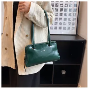 Detail of dark green leather shoulder bag on a beige corduroy suit for vintage commute style