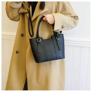 Detail of black lychee grain leather handbag featuring gold hardware and adjustable strap
