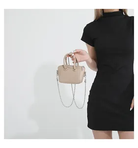 Detail of beige mini crossbody bag with litchi texture and silver bead chain strap