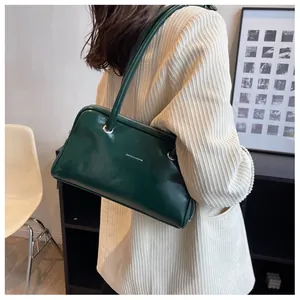 Detail of forest green patent leather underarm bag with silver ring and shoulder strap