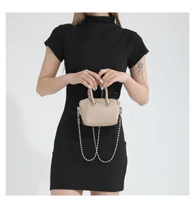 Detail of beige mini crossbody bag with litchi grain texture and silver bead chain strap