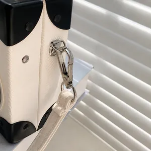 Macro detail of a detachable silver hook on a Saffiano texture radio box bag