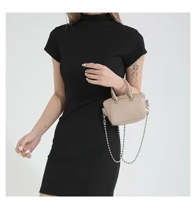 Detail of a beige mini handbag with silver bead chain shown on a black dress