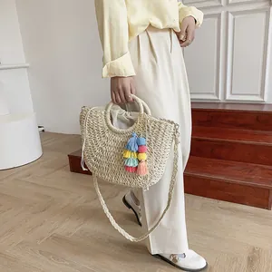 Detail of bohemian straw bag with colorful tassels, round handle and drawstring lining
