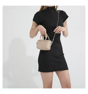 Close-up of beige mini Boston bag featuring leather texture and silver chain strap