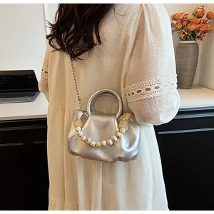 Détail du sac argenté plissé avec poignée en perles marbrées et chaîne en métal