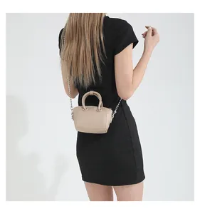Mini beige top-handle bag with silver chain strap shown on a model for scale