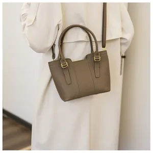 Detail of dark khaki pebbled leather bucket bag with top handle and golden hardware