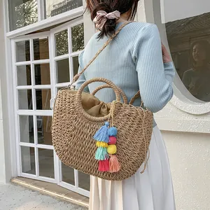 Detail of bohemian straw bag with colorful layered tassels and wooden handles