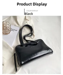 Detail of a sleek black patent faux leather underarm bag with slim straps and silver zipper