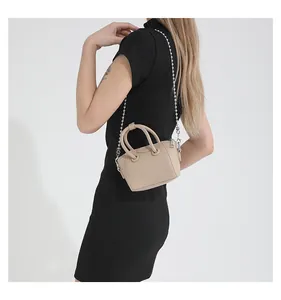 Detail view of a mini beige tote bag with litchi grain texture and silver chain strap