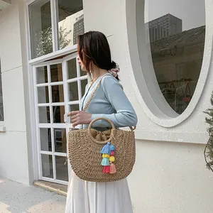 Detailed straw woven semi-circle bag featuring vibrant colorful tassels and drawstring