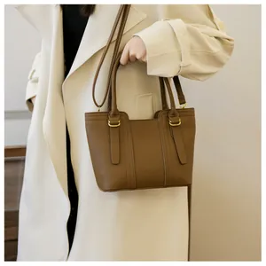 Close-up of brown pebbled leather tote bag with elegant gold hardware on a stylish model