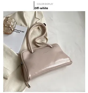 Detailed view of an off-white glossy faux leather shoulder bag on an elegant background