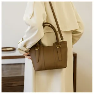 Close-up of brown pebbled leather tote bag featuring gold hardware and stitched details