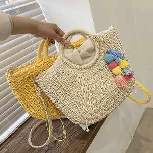 Detail of handmade straw tote bags with woven texture, round handles and tassel charm