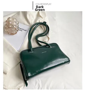 Detailed close-up of dark green glossy leather handbag with silver zipper and logo
