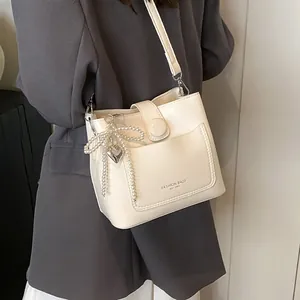 Sac seau minimaliste crème avec breloque nœud en perles et pendentif en cœur