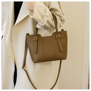 Close-up of brown litchi pattern leather handbag with gold-tone hardware and stitching