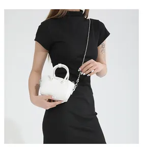 Detail of white micro handbag with lychee pattern leather and silver chain strap