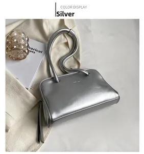 Close-up of stylish silver metallic shoulder bag with long straps on a soft background