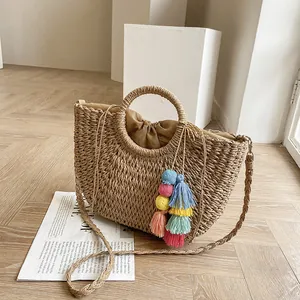 Detail of bohemian straw handbag with circular handles and colorful tassel charm