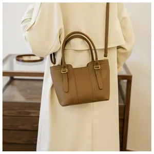Brown lychee leather bucket bag with gold hardware worn over a beige trench coat